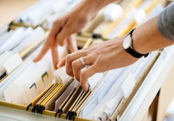 Close-up of hands searching in a file cabinet